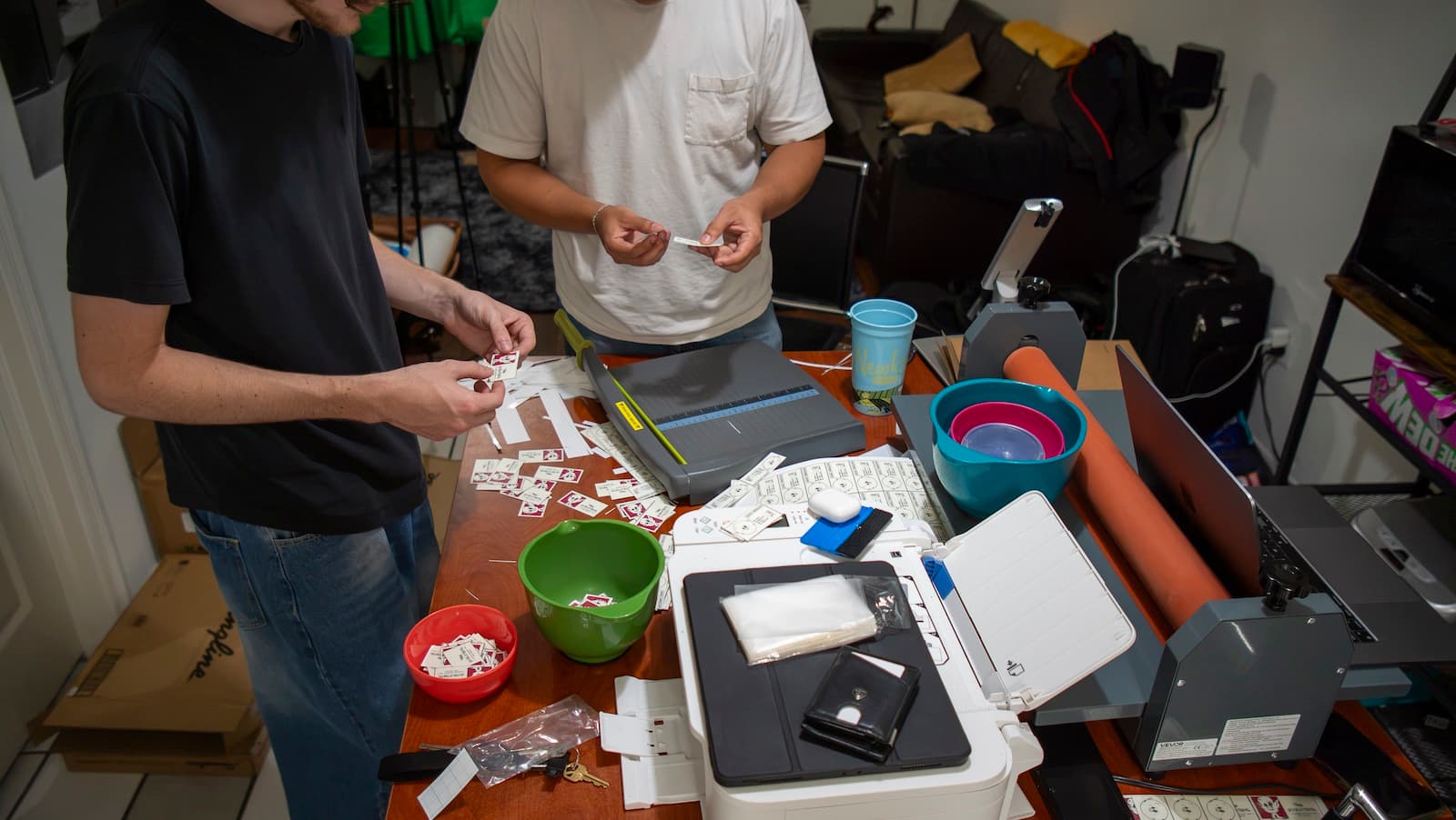 Two team members cutting and sorting printed card stickers at a work table